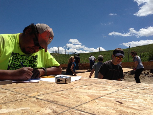 Yazzie, who our Mission of LOVE volunteers built a home for, going over the blueprints made on cardboard for the LOVE home being built.