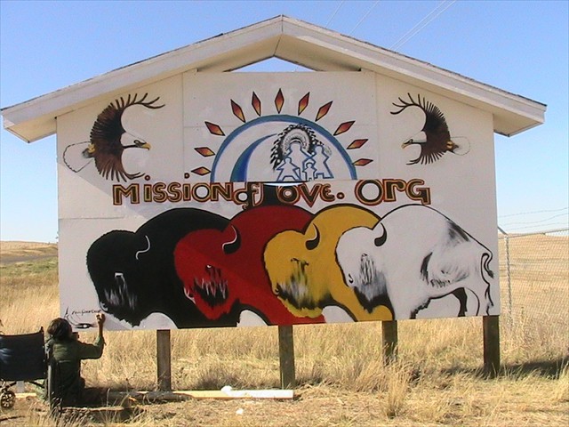 Lakota artist Kevin Poor Bear painting our Mission of LOVE Lakota logo in Kyle, S.D. Kevin started this artwork with only one pencil, is afraid of heights, and has no legs and only gets around in a wheel chair to sell his artwork to feed his family. This was completed in two days.