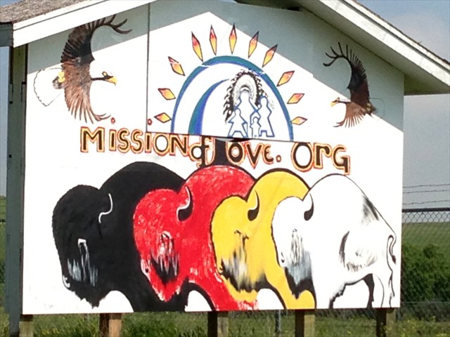 Mission of LOVE logo painted by Lakota artist, Kevin Poor Bear on a billboard in Kyle, S.D.